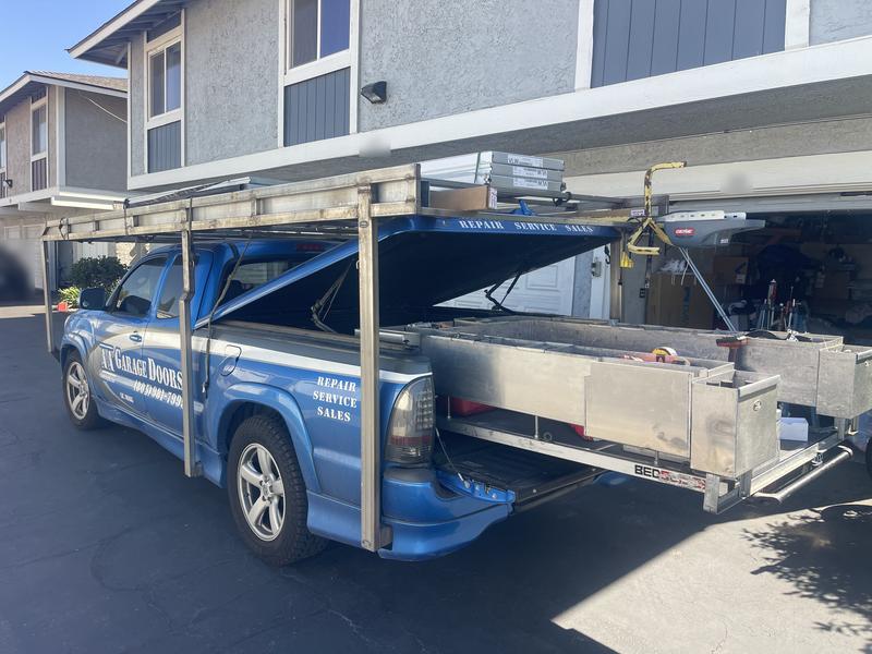 AA Garage Doors service truck with slide-out parts drawers open, stocked with springs, cables and hardware for same-day repairs