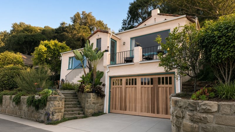 Custom natural wood carriage-style garage door with window tops on a Spanish-style home in Santa Barbara