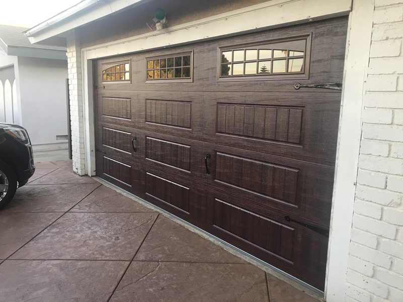 Dark wood-grain carriage, window tops garage door installed by AA Garage Doors