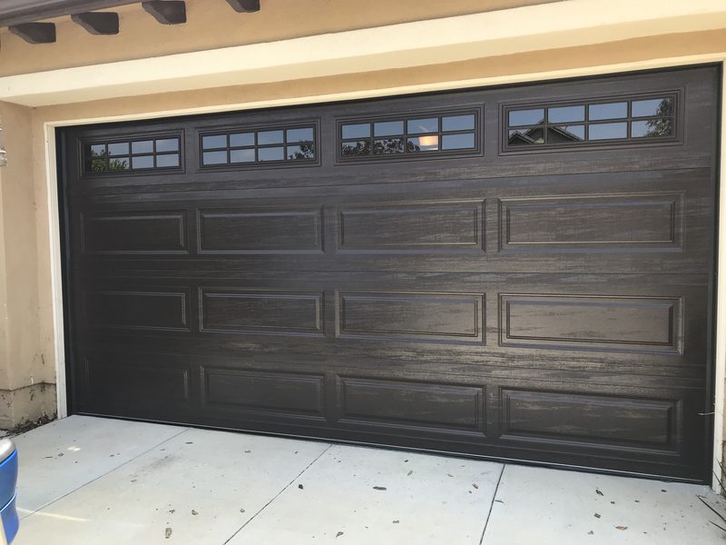 Dark wood-grain raised panel, window tops garage door installed by AA Garage Doors