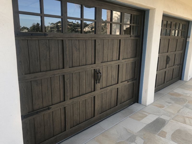 Dark wood-look carriage-style garage doors with large grid windows and black handles