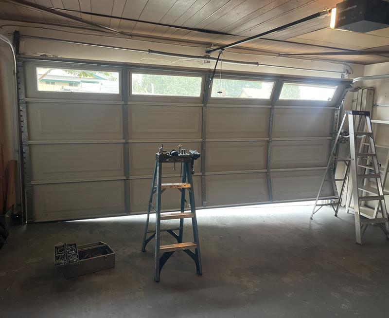 Inside view of a crooked garage door with a gap at the bottom