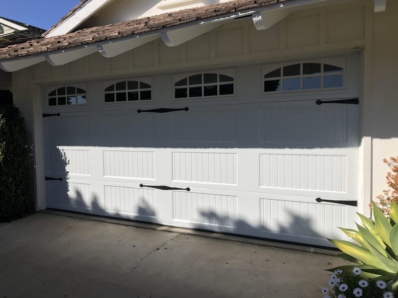 White carriage house, arched windows and black hardware garage door installed by AA Garage Doors