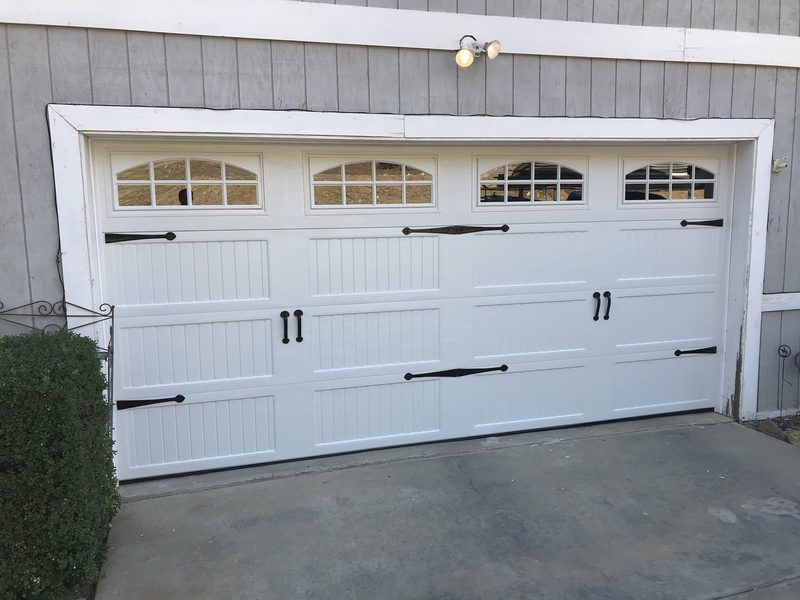 White carriage house, arched windows, black handles garage door installed by AA Garage Doors